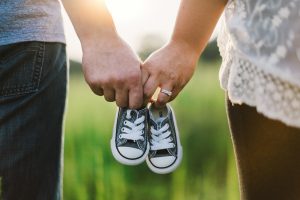 Baby footprint art is inspired by this photo of a couple holding hands and a pair of baby shoes.