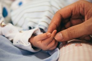 Baby footprint & hand print keepsakes are inspired by this close up picture of two hands. A parent's hand holding a baby's.